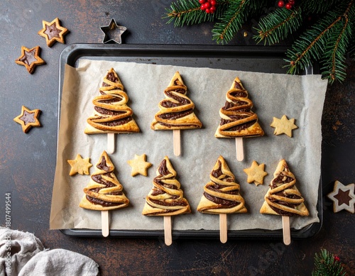 Christmas tree–shaped chocolate pastry pops on wooden sticks, baked on parchment with star cookies, festive holiday scene with warm lighting and rustic decor.