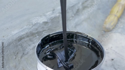 Mixing bituminous waterproofing putty in a new can for use in construction. The putty is sticky and thick. It protects buildings from water. Protect residential and commercial building