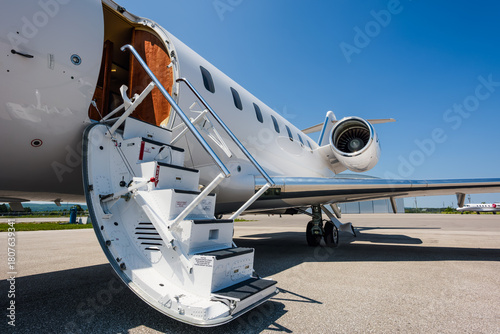 Wide-angle view of an open jet entry door with integrated air stair, shown from the front left of the aircraft on a clear day, highlighting structure, hinges, and step details.