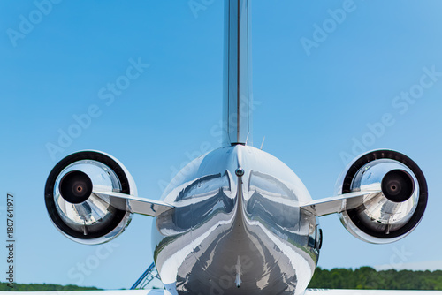 Quadro su tela Centered rear view of a private jet showing both engines, tail section, polished surfaces, and clear sky lighting from a straight-on position