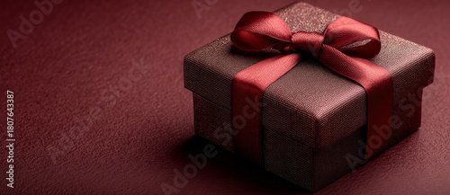 Beautiful Wrapped Gift Box With a Red Bow on a Simple Burgundy Background