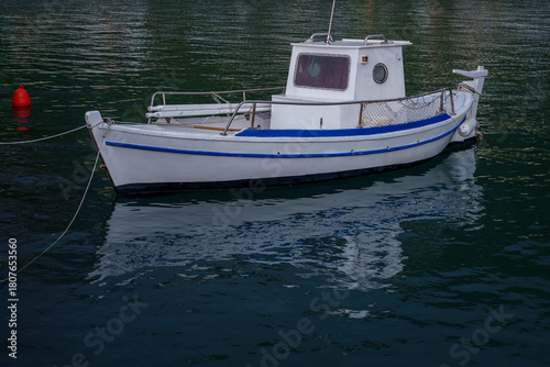 Small white fishing boat moored on calm water
