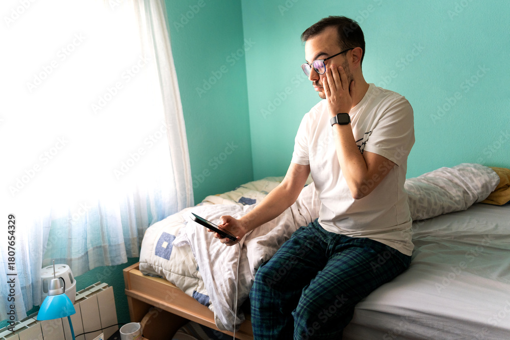 Fototapeta premium Freelance programmer man waking up checking smartphone in bed