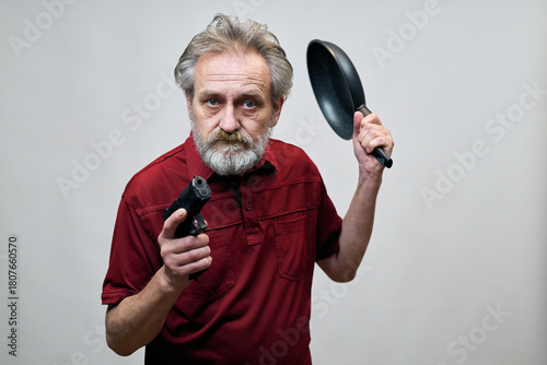 Older man with wrinkles on face skin posing as aggressor in studio