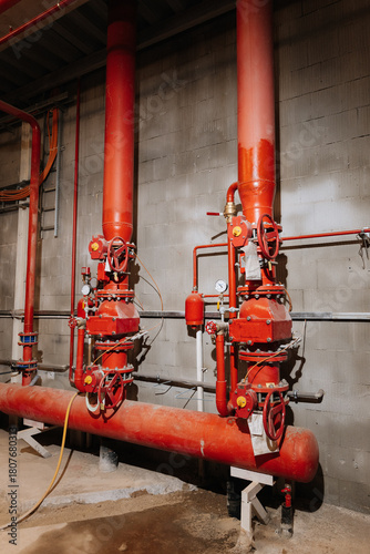 Fire sprinkler valves and red pipes in industrial plant, safety equipment, vertical view