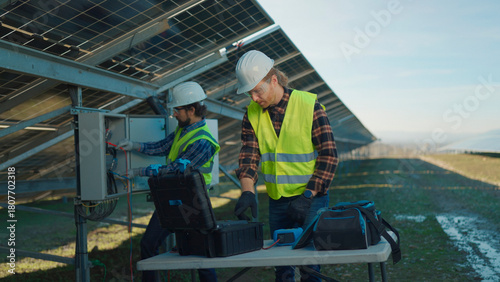 Workers inspect solar panels on a sunny day in a renewable energy field
