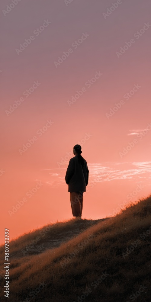 Fototapeta premium Silhouette of female at sunset on a grassy hill
