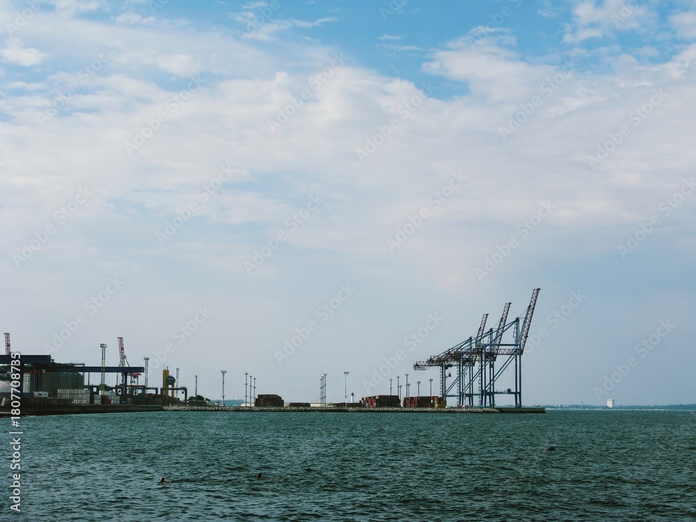 Fototapeta premium Cargo cranes of modern sea terminal under wide cloudy sky