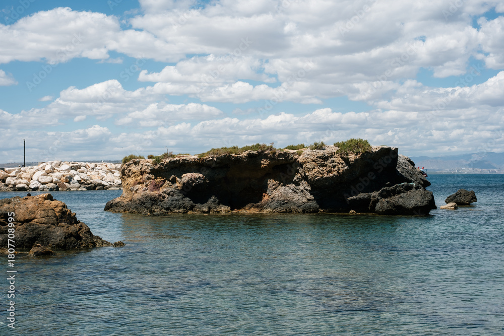 Fototapeta premium Coastal rock formations with clear blue water under a cloudy sky