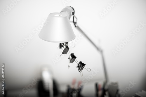 Desk lamp with paper clips hanging under neath the lamp shade