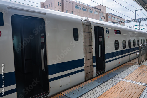 Photos A white Shinkansen with blue stripes stops at an Osaka station platform