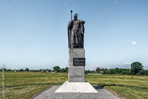 фотографія Bronze statue of Petro Kalnyshevsky standing in an open field with village backdrop, honoring the last Cossack hetman of Zaporizhzhia Sich