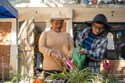 Mexican grandmother and grandson bonding through gardening, planting flowers