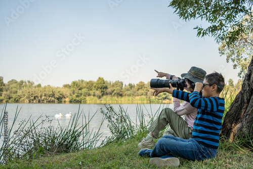 Mother and son birdwatching by the lake, enjoying nature and a family outdoor activity