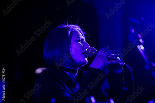 Konstfotografi Female singer performing on stage under blue lights