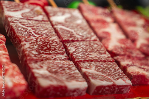 Photography Close up rows of wagyu beef skewers in Kyoto show deep red meat and white fat, w