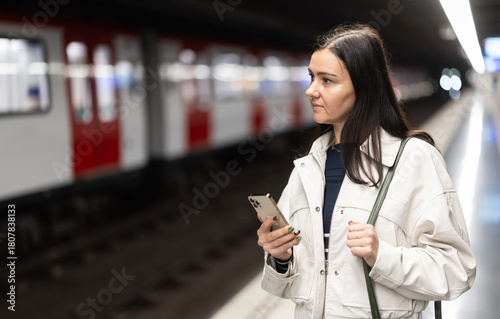 Obraz na plátně Woman stands with mobile phone at subway station