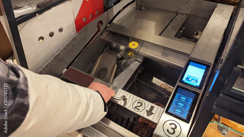 Hand using modern automatic bread slicing machine in self-service bakery section