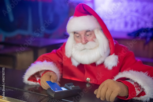 Santa Claus pays with a credit card at a pub. 