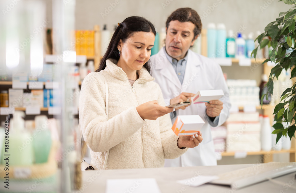 Fototapeta premium Female scans code on pill label. Male pharmacist offers to choose the right medicine