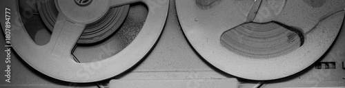 A close-up black and white photograph of an old tape recorder and a player for vinyl records and reel-to-reel tapes