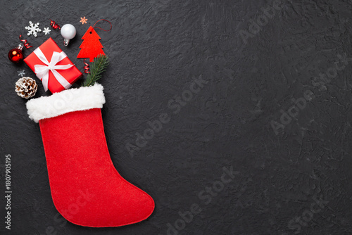 Christmas sock with gifts and decoration on concrete background, top view