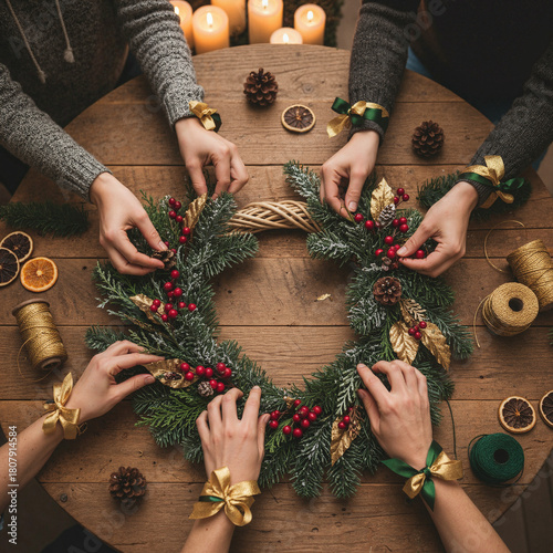 Group crafting festive Christmas wreath, joyful mood, decorating with pine and berries at wooden table with candlelight, with copy space