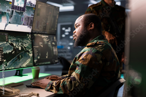 Army operative conducts tactical reconnaissance, utilizing equipment for data analysis and mission planning. Air defense forces agent looks at aerial map on screen, pinpointing targets