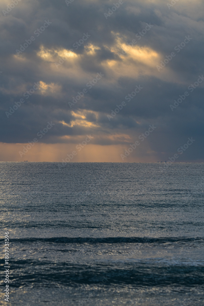 Obraz premium Epic Ocean Sunrise with Golden Sunbeams and Cloudy Sky