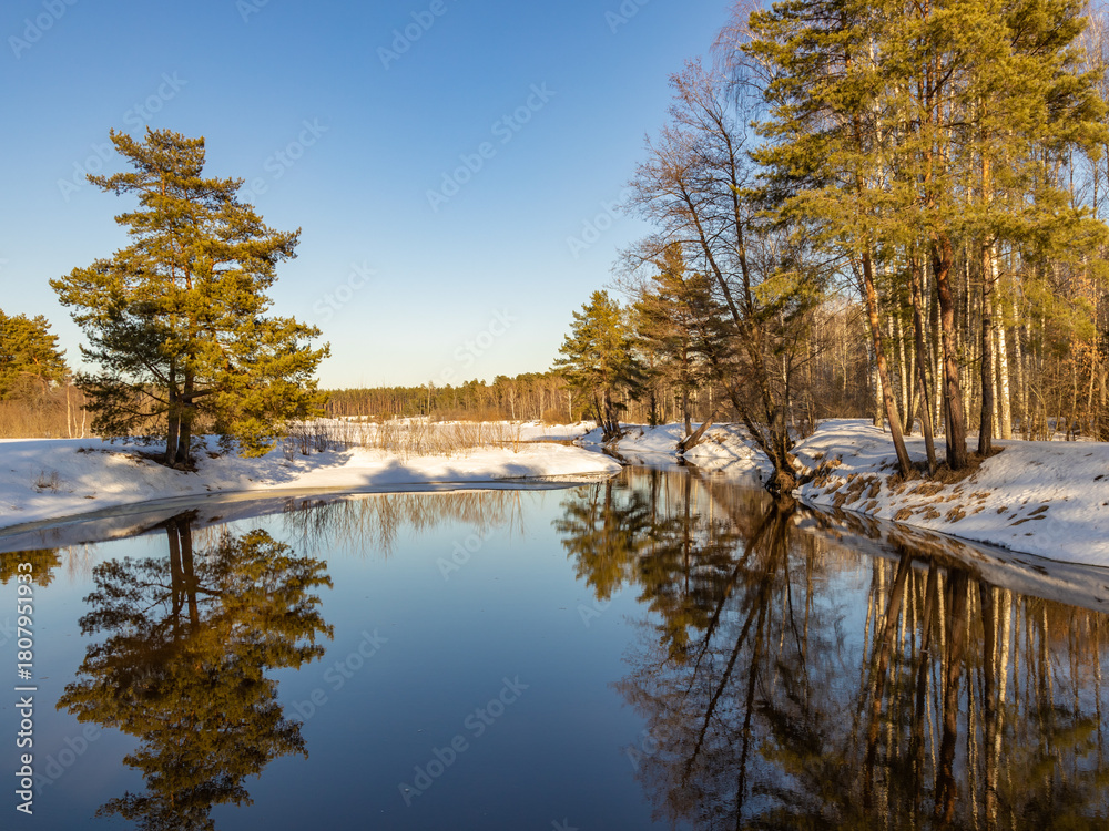 Obraz premium Serene winter scene with a body of water reflecting the sky and trees