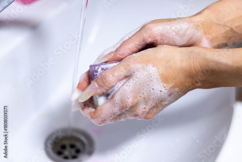 girl washes her hands with soap under running water