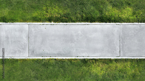 Concrete road grass lawn sidewalk aerial view top view paved path concrete road with green grass either side and soft sunlight casting subtle shadow, peaceful suburban walkway lined by maintained