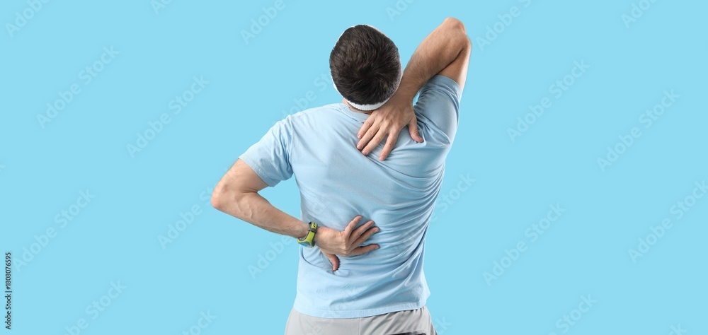 Obraz premium Sporty young man suffering from back pain on blue background