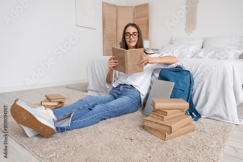 Young woman reading book on floor in cozy bedroom, student lifestyle and home...
