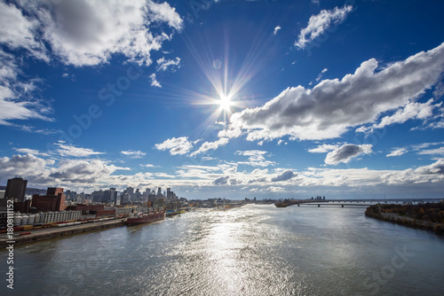 Wide view of a cargo ship at the industrial port of Montreal on the St Lawrence River, with the downtown skyline and business district visible behind in Quebec Canada, North America.