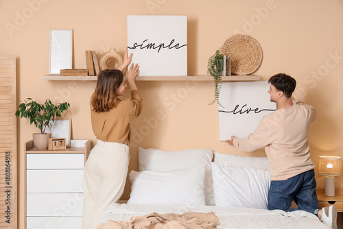 Young couple hanging poster...