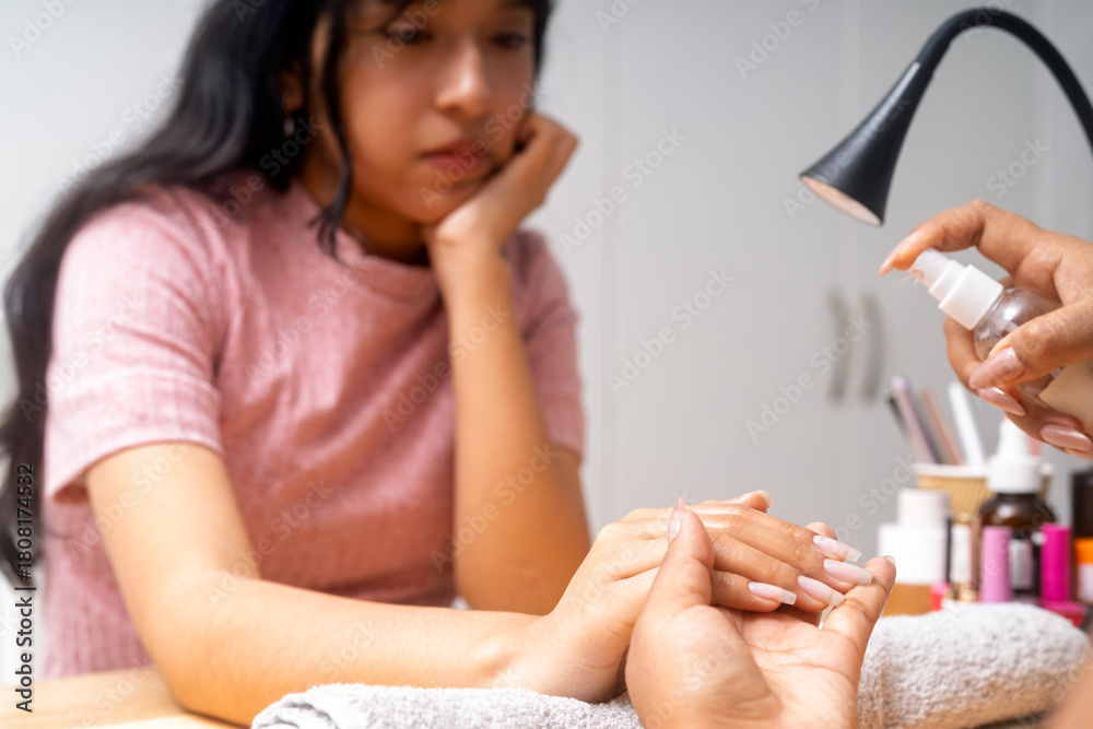 Fototapeta premium Client receiving professional manicure service with hand spray