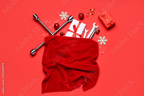 Santa bag with wrenches, presents and Christmas decor on red background
