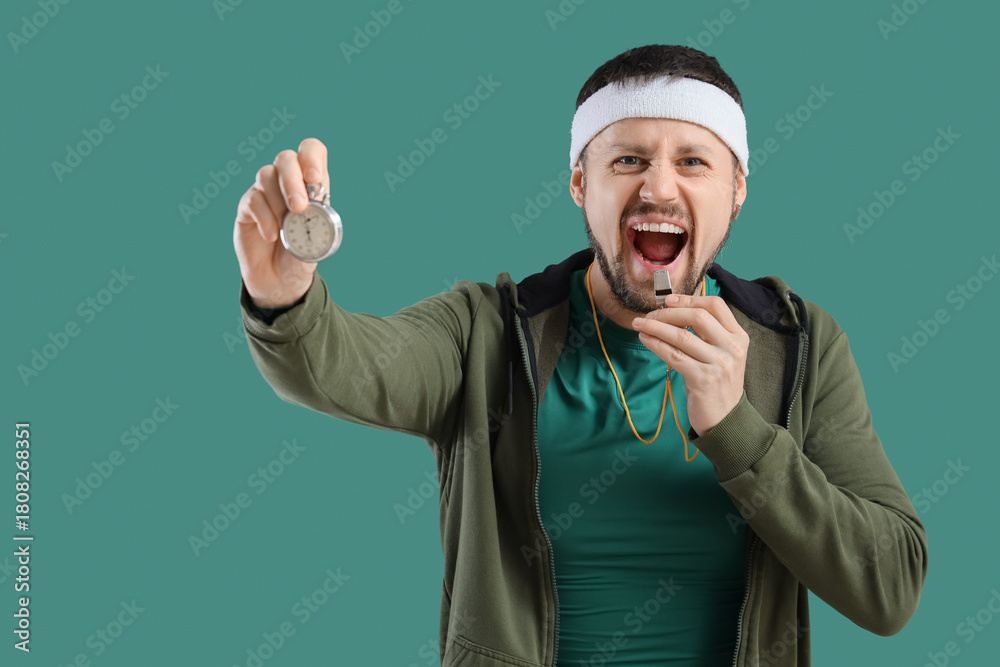 Fototapeta premium Male trainer with whistle and stopwatch on green background