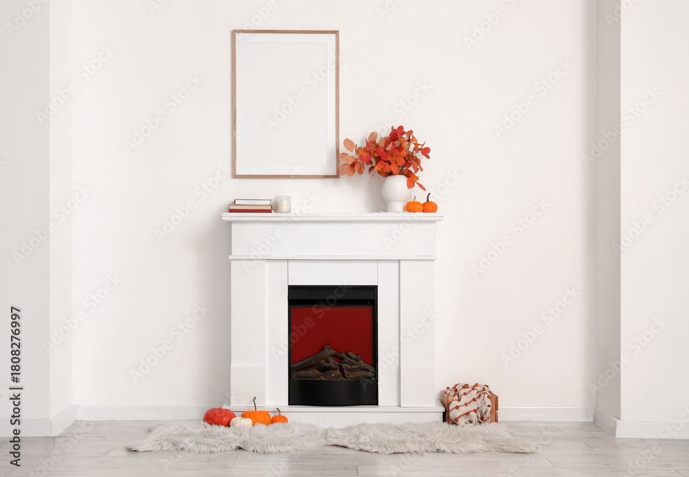 Fototapeta premium Fireplace, pumpkins and vase with beautiful autumn leaves in interior of living room