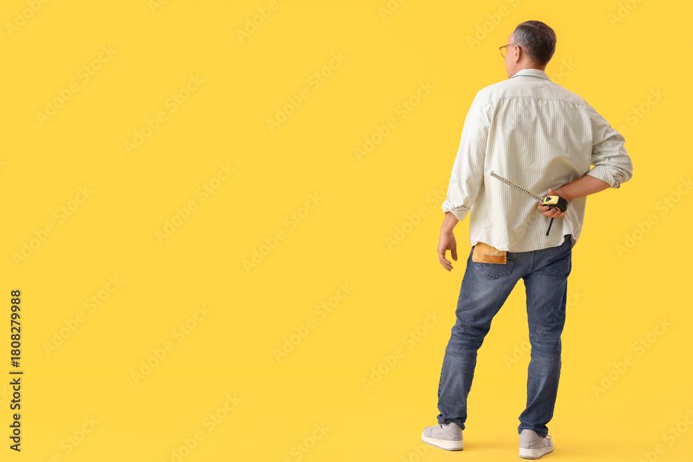 Naklejka premium Mature man with tape measure on yellow background, back view