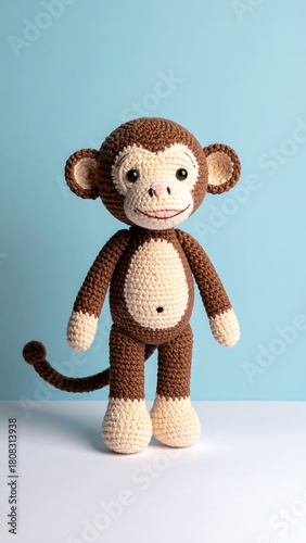 Amigurumi monkey standing against a pale blue background on a white surface, charming homemade look, brown and cream colors