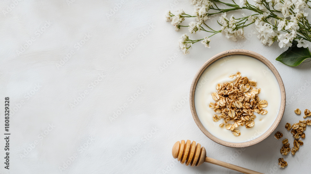 Fototapeta premium Creamy yogurt bowl with granola and honey dipper, gentle sunlit flatlay