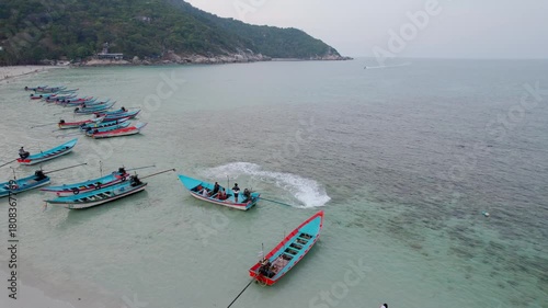 A cinematic tracking drone shot of a boat in the sea with people on board. swim around and then swimming away.