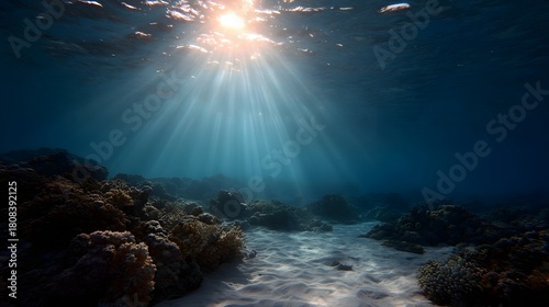 Fototapeta Naklejka Na Ścianę i Meble -  Sunlight streams through the deep ocean water illuminating a vibrant coral reef and sandy seabed at dusk