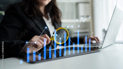 Foto A business professional focused on analyzing data trends using a magnifying glass on a laptop, showcasing graphs and charts to uncover financial insights