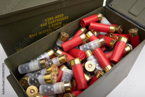 Pile of 12 gauge bullet shotgun shell in green army ammo crate on white background