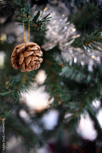 Delightful golden pinecone ornament hangs gracefully on an evergreen christmas tree branch, bringing festive and warm holiday decoration. scene evokes pure winter joy