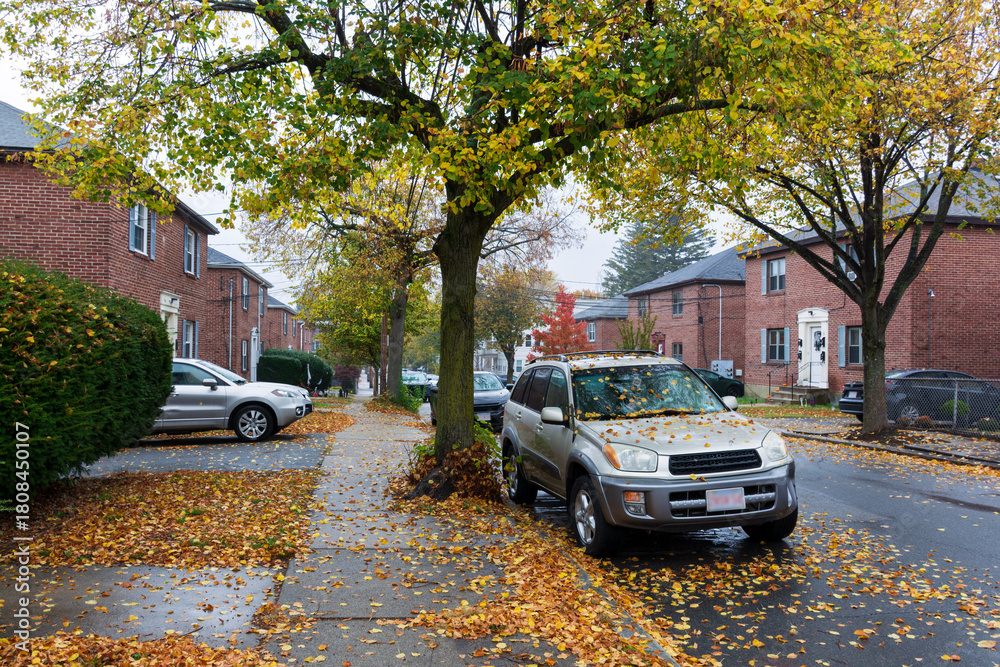 Naklejka premium Silver suv parked along a leafy sidewalk on a rainy autumn day in Brighton, Boston area, Massachusetts, USA