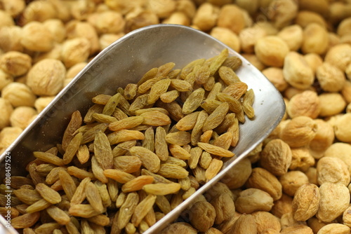 Golden raisins kishmish with silver scoop showing dried grape texture natural sweetness closeup
